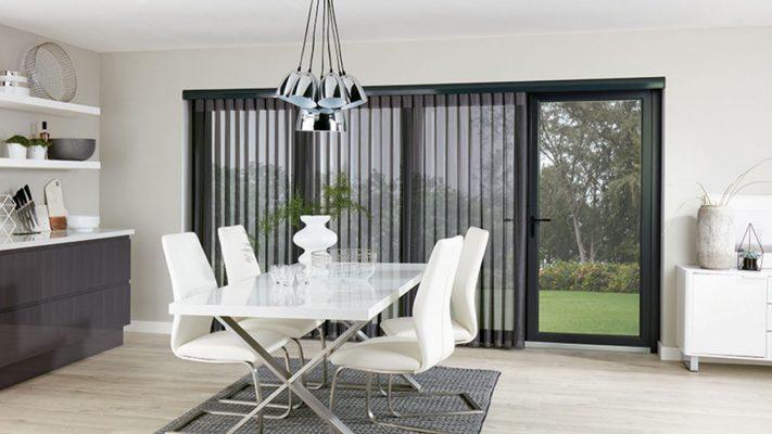 Modern interior with black vertical blinds and sliding glass door.