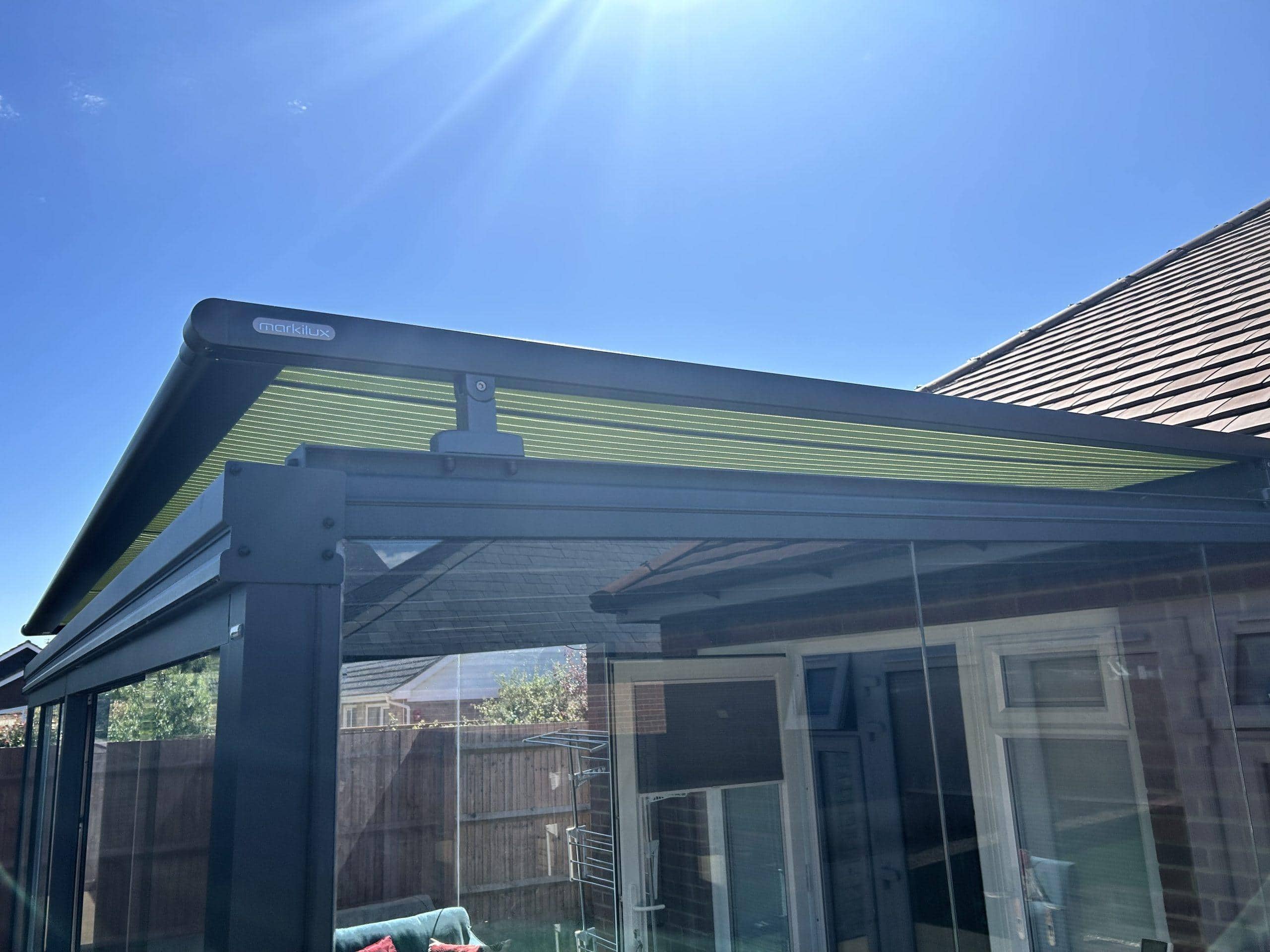 Outdoor glass canopy with shading system for patio or garden.