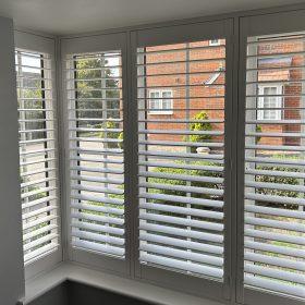 Modern white window shutters with adjustable slats for privacy and light control.