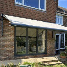 Modern retractable awning installed on a brick house for sun protection and outdoor comfort.
