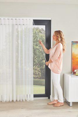 Woman operating a remote-controlled sheer curtain for shading and privacy.