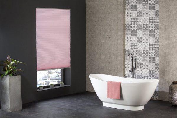 Pink roller blind for bathroom window shading and privacy.