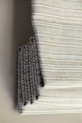 Modern fabric window blind with layered pleats and textured fabric.