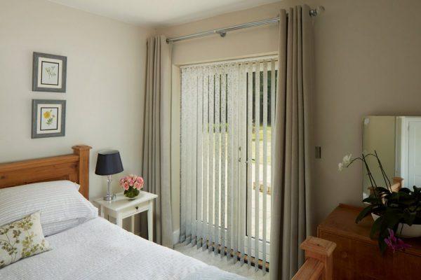 Vertical blinds from Sovereign Shading Systems providing privacy and light control in a modern bedro.