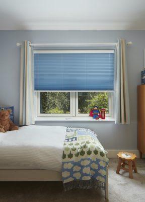 Blue window blinds with white curtains in a modern bedroom setting.