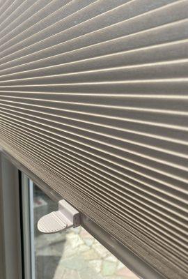 Modern beige pleated window blinds for shading and privacy.