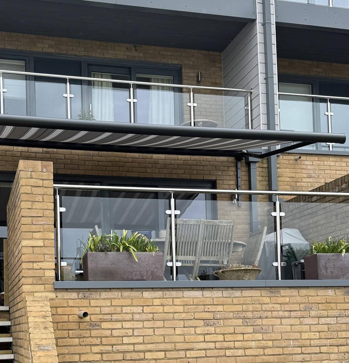 Modern balcony with sleek shading system and glass balustrades for sun protection.