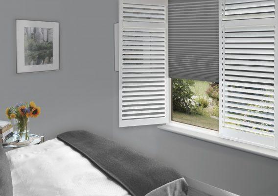Modern window with white louvered blinds and roller shade, ideal for shading solutions.