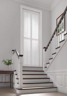 Elegant white window shutters with adjustable slats for light control.