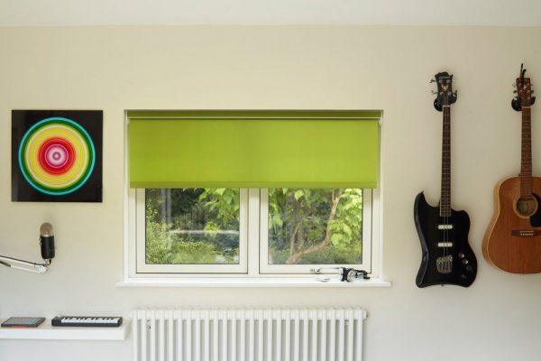 Green window blind installed in a modern room with musical instruments on the wall.
