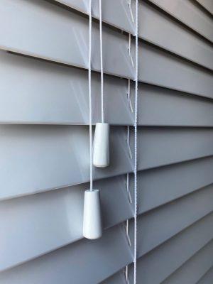 Modern window blinds with adjustable slats and pull cords for shading control.