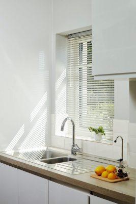 Modern kitchen with window blinds and natural light.