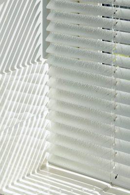 Modern white window blinds with shadow patterns, ideal for shading solutions.