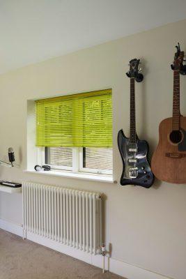 Interior with green window blinds and musical guitars on the wall.