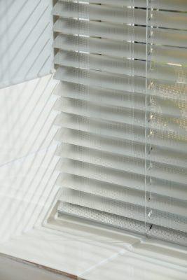 Modern white Venetian blinds controlling light and privacy in a bright room.