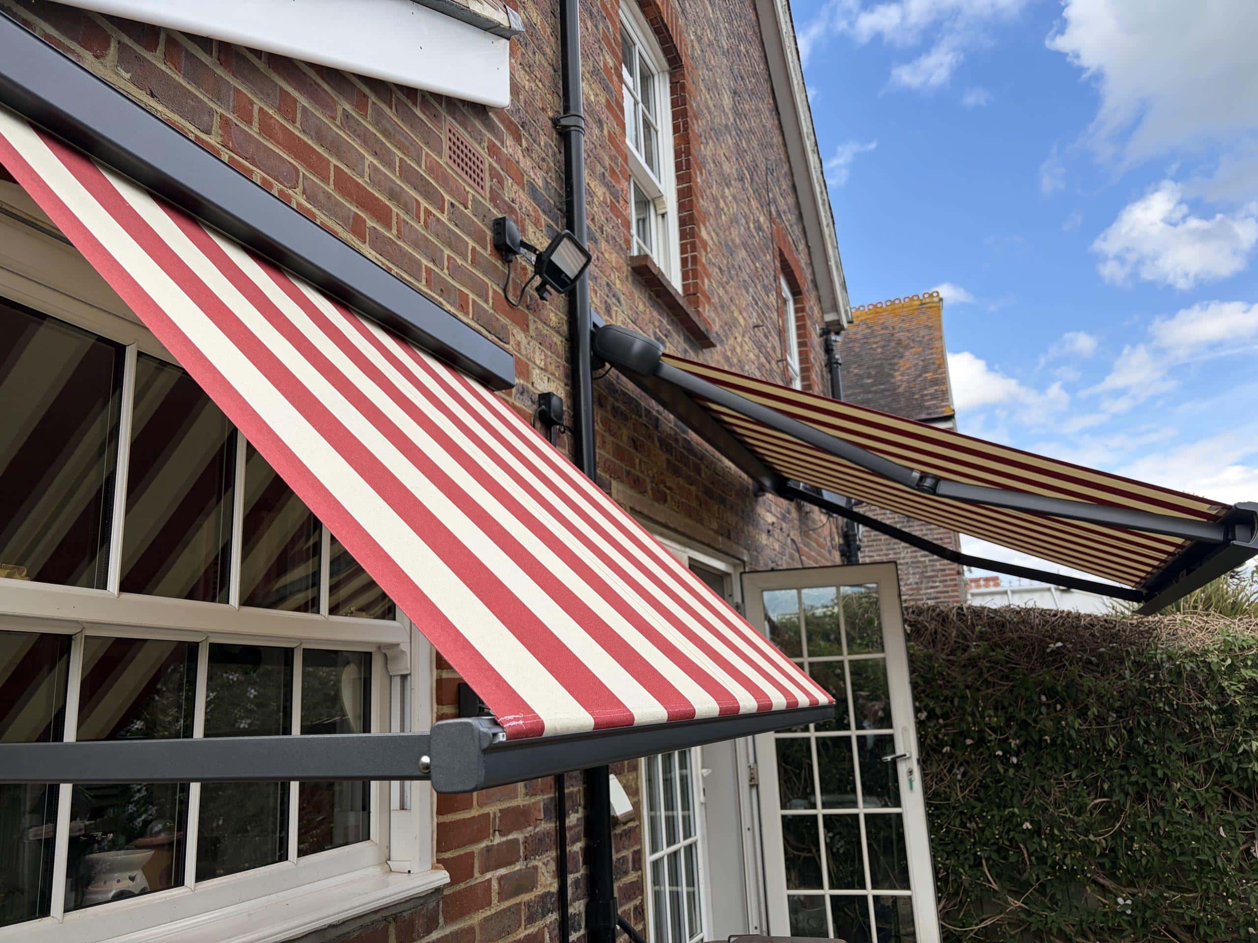 Retractable striped awning providing shade and style for a residential property.